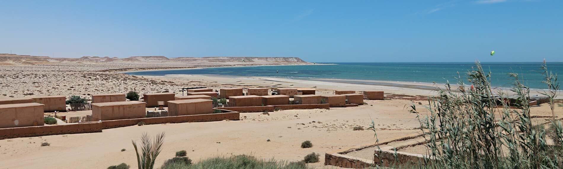 Wüstenresort in Dakhla mit Hütten am Meer, Strand und Himmel im Hintergrund.