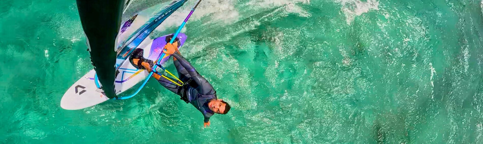 Mauritius - Le Morne - Luftaufnahme eines Windsurfers in Bewegung auf t&uuml;rkisfarbenem Wasser, umgeben von Wellen und Gischt.