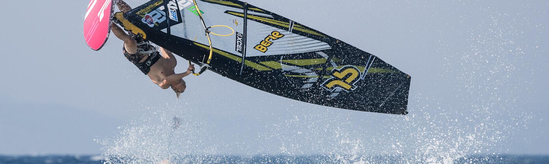 Windsurfer führt einen Sprung über Wellen aus, blauer Himmel im Hintergrund, in Theologos auf Rhodos