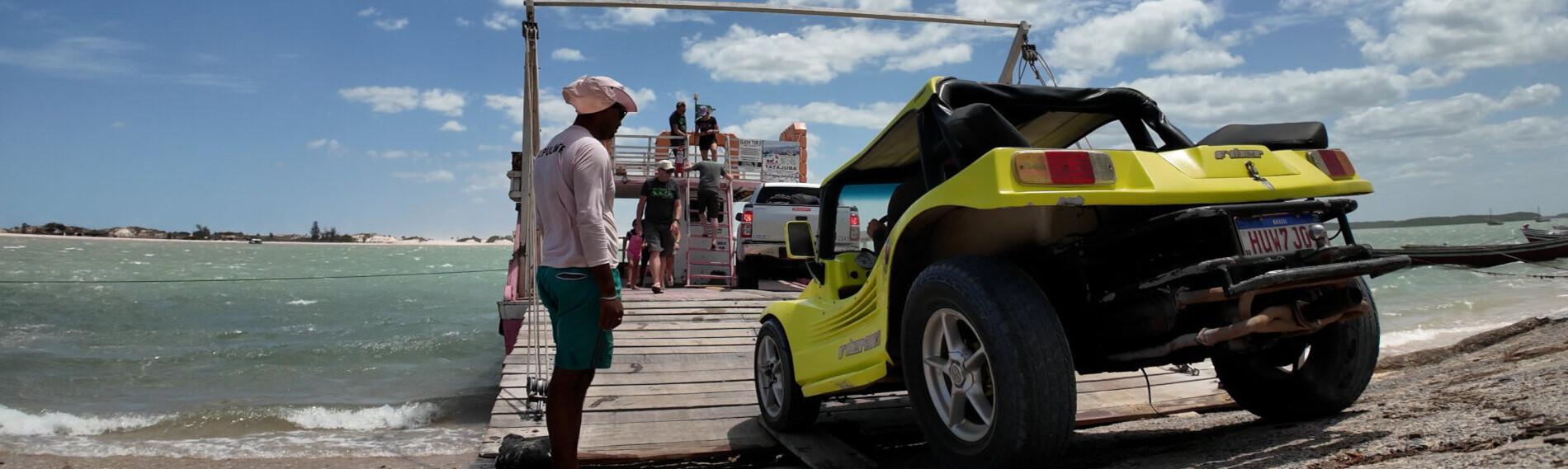 Menschen am Strand gehen auf eine Fähre nach Jericoacoara zu, neben ihnen ein gelber Jeep