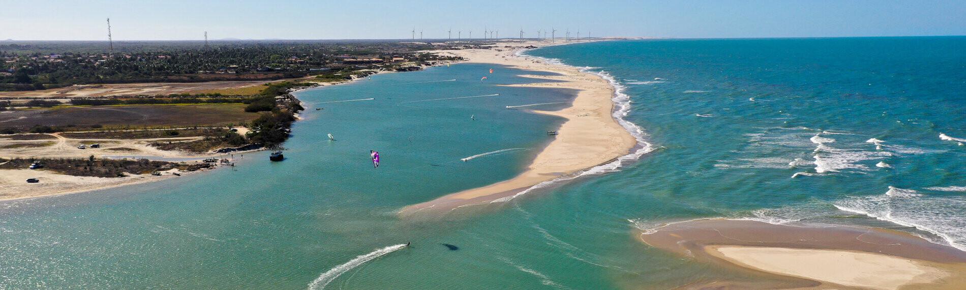 Luftaufnahme der Küstenlandschaft von Parajuru mit Strand, Flussmündung und Kite- und Wingsurfer.