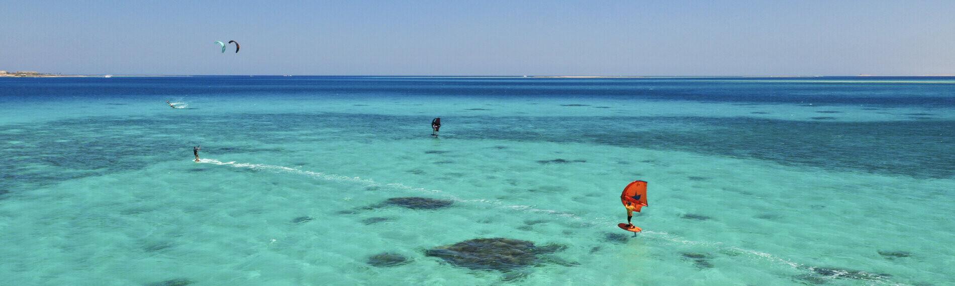 Kitesurfer und Wingsurfer auf türkisfarbenem Meer mit klarem Himmel in Ras Soma Ägypten, KBC Ras Soma.