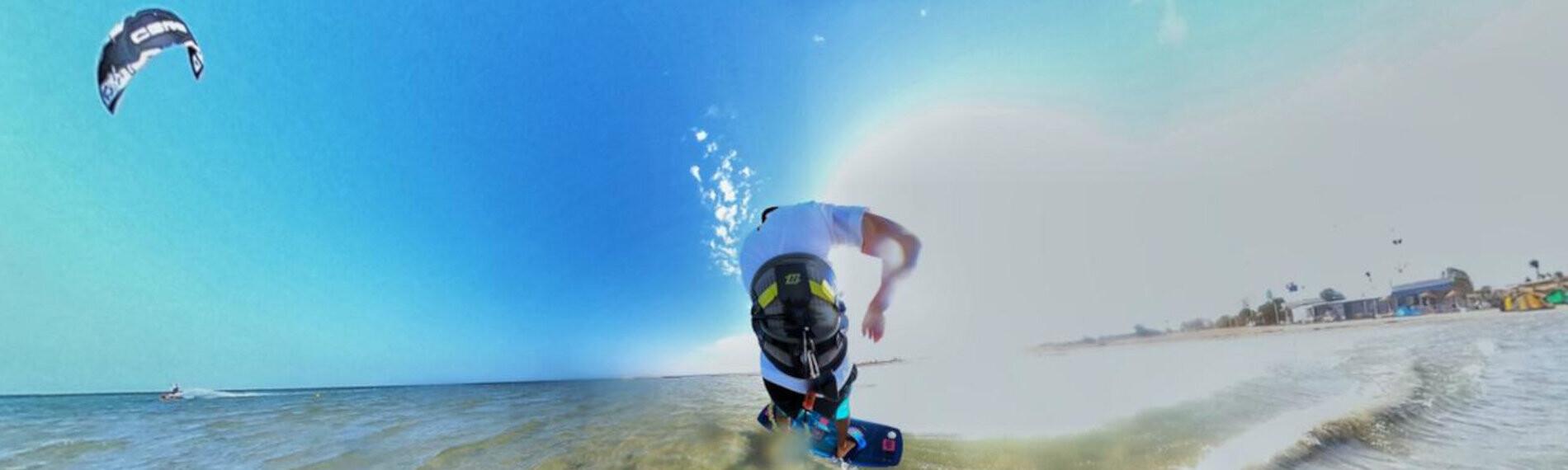 Kitesurfer gleitet bei sonnigem Wetter über flaches Wasser vor dem Les Dauphins Kitecenter auf Djerba.