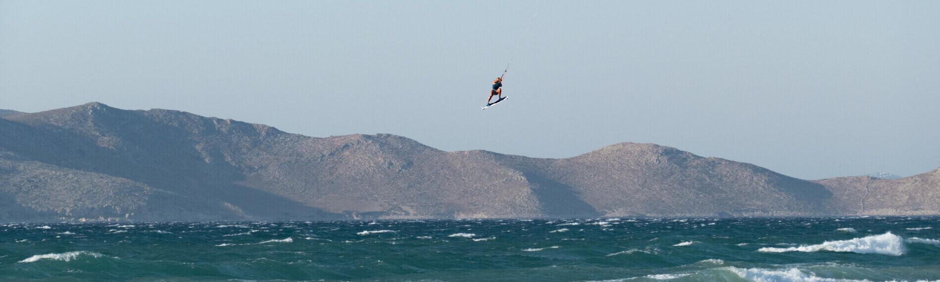 Kitesurfer springt über wellige See mit Bergen von Marmari auf Kos im Hintergrund