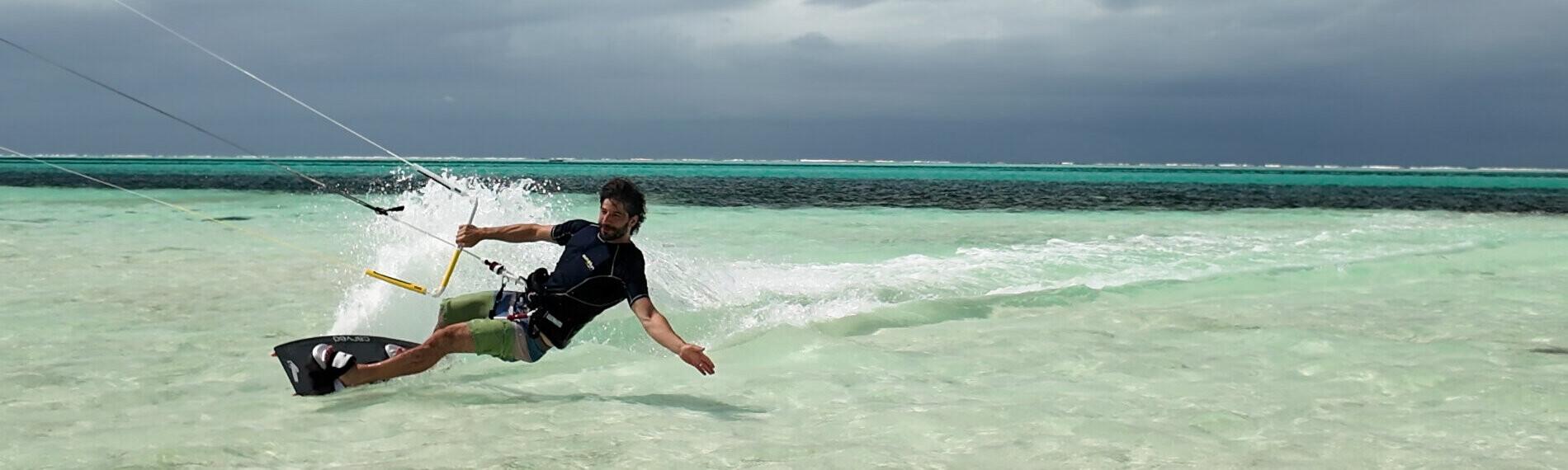 Kenia Kitesurfer gleitet über flaches türkisfarbenes Wasser unter bewölktem Himmel.
