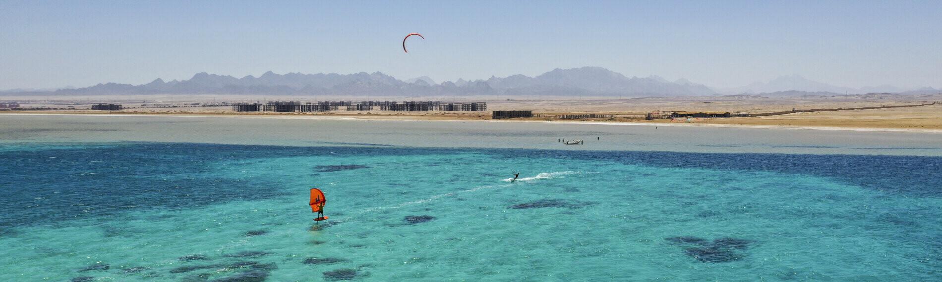 Kitesurfer in Ras Soma, Ägypten auf türkisfarbenem Meer vor Wüstenkulisse.