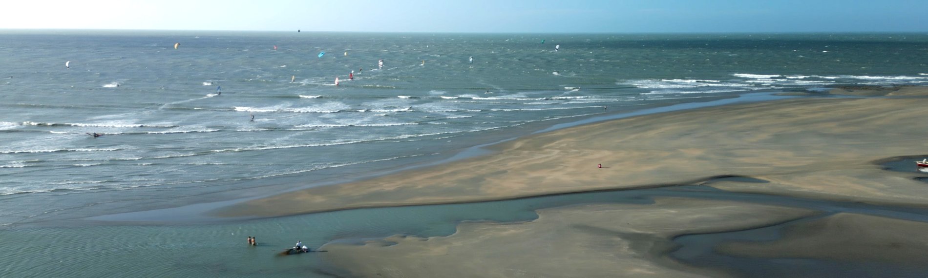 Luftaufnahme eines Strandes vor Maceio, Brasilien mit Windsurfern auf dem Meer.